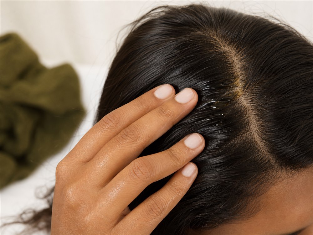 Fingertips gently applying oil to a healthy scalp